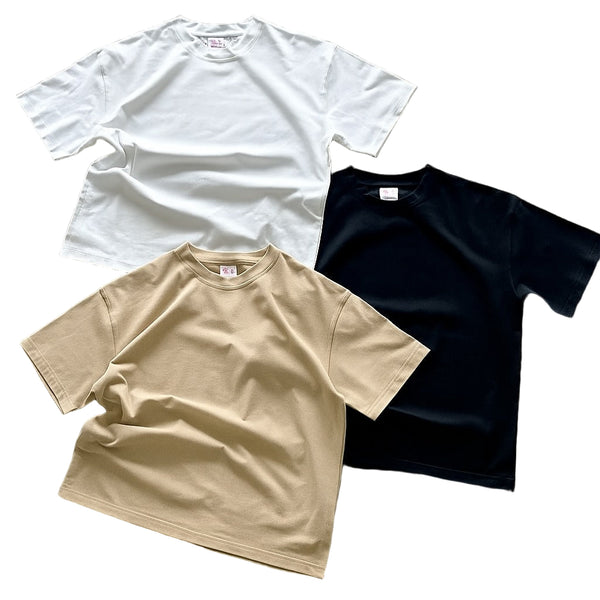 Three plain t-shirts in white, beige, and black on a white background