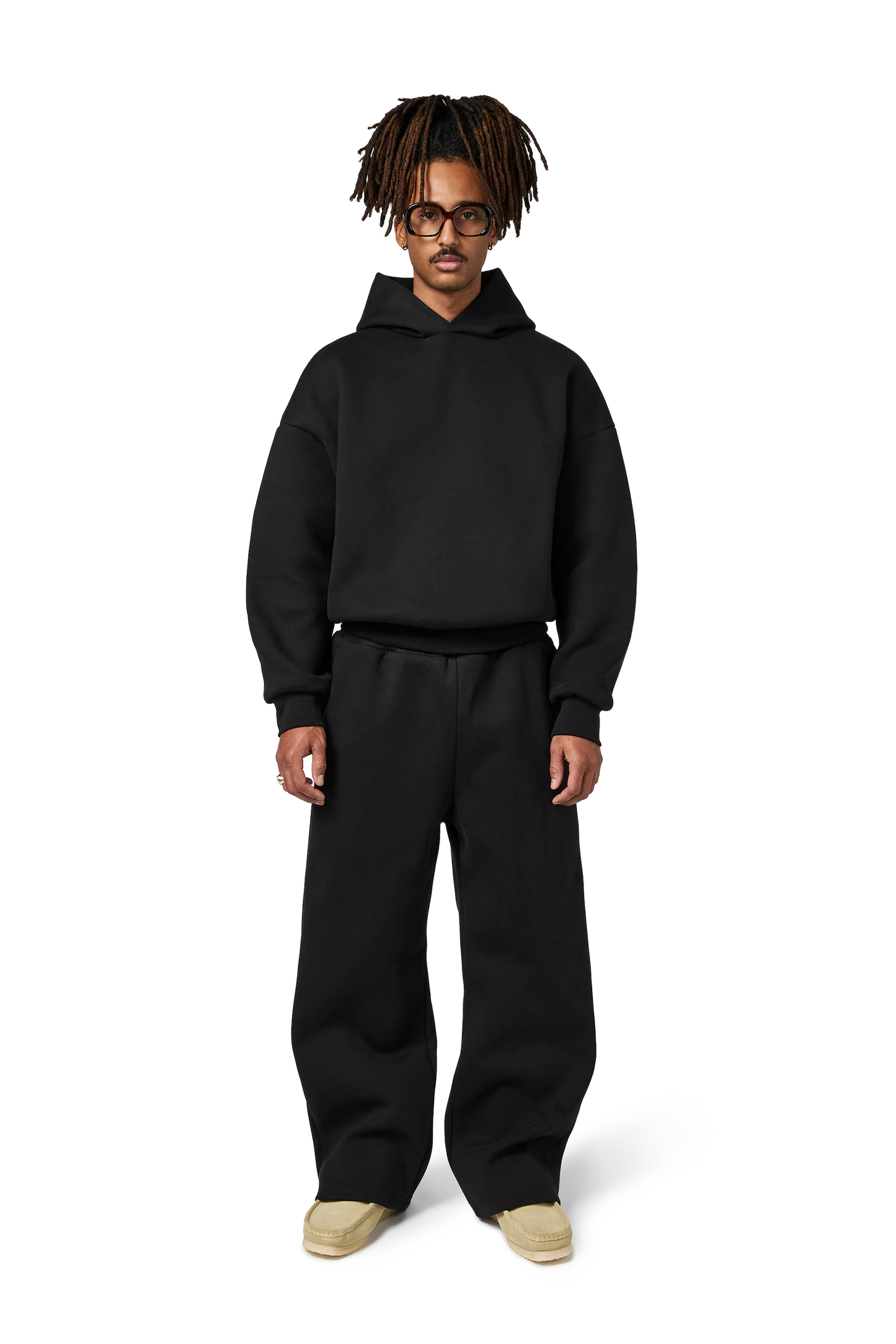 Person wearing a black hoodie and pants on a white background