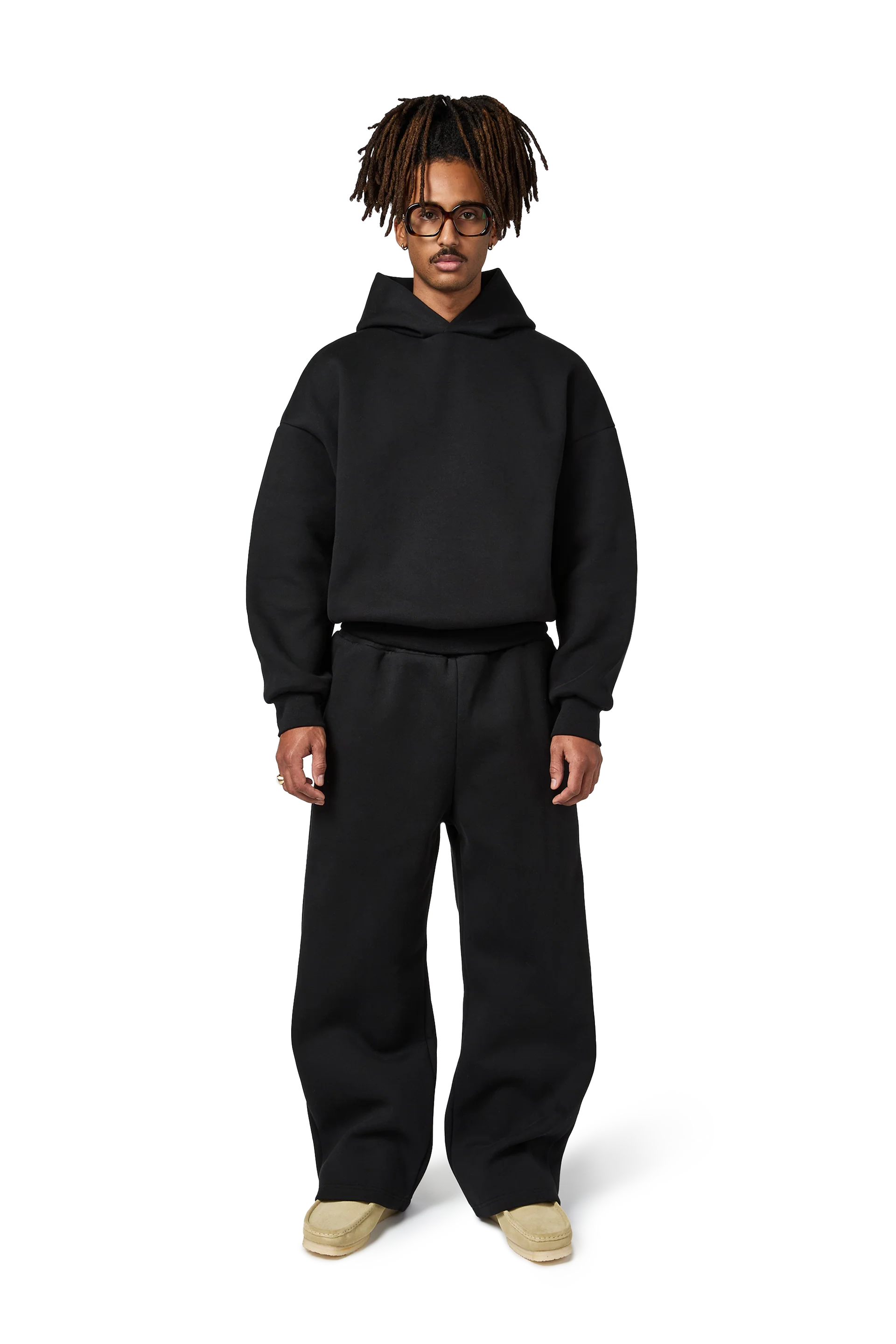 Person wearing a black hoodie and pants on a white background