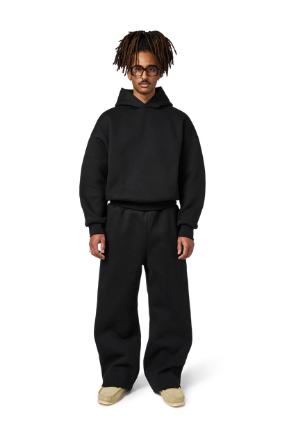 Person wearing a black hoodie and pants on a white background